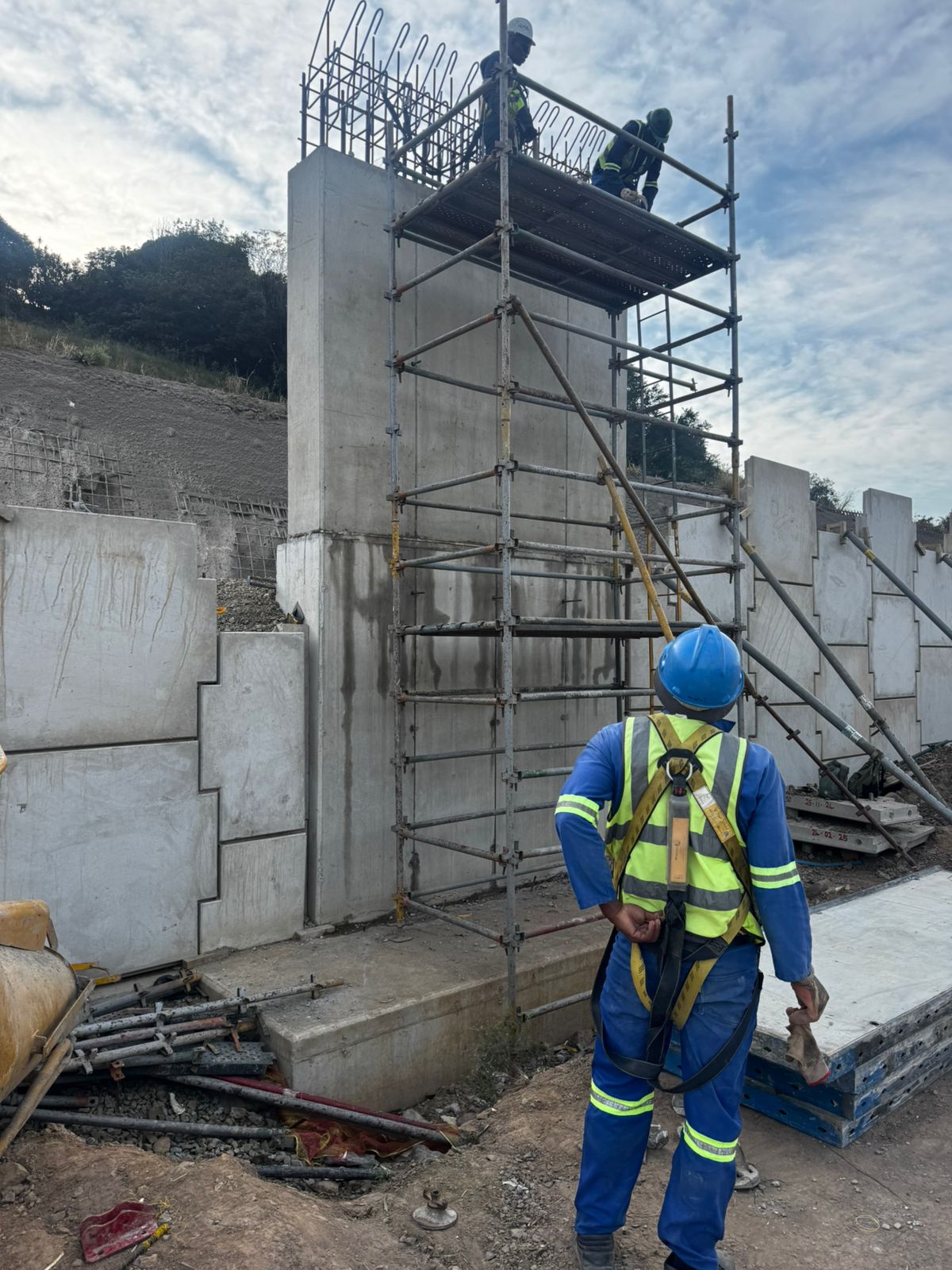 Construction worker on site with scaffolding and concrete structures